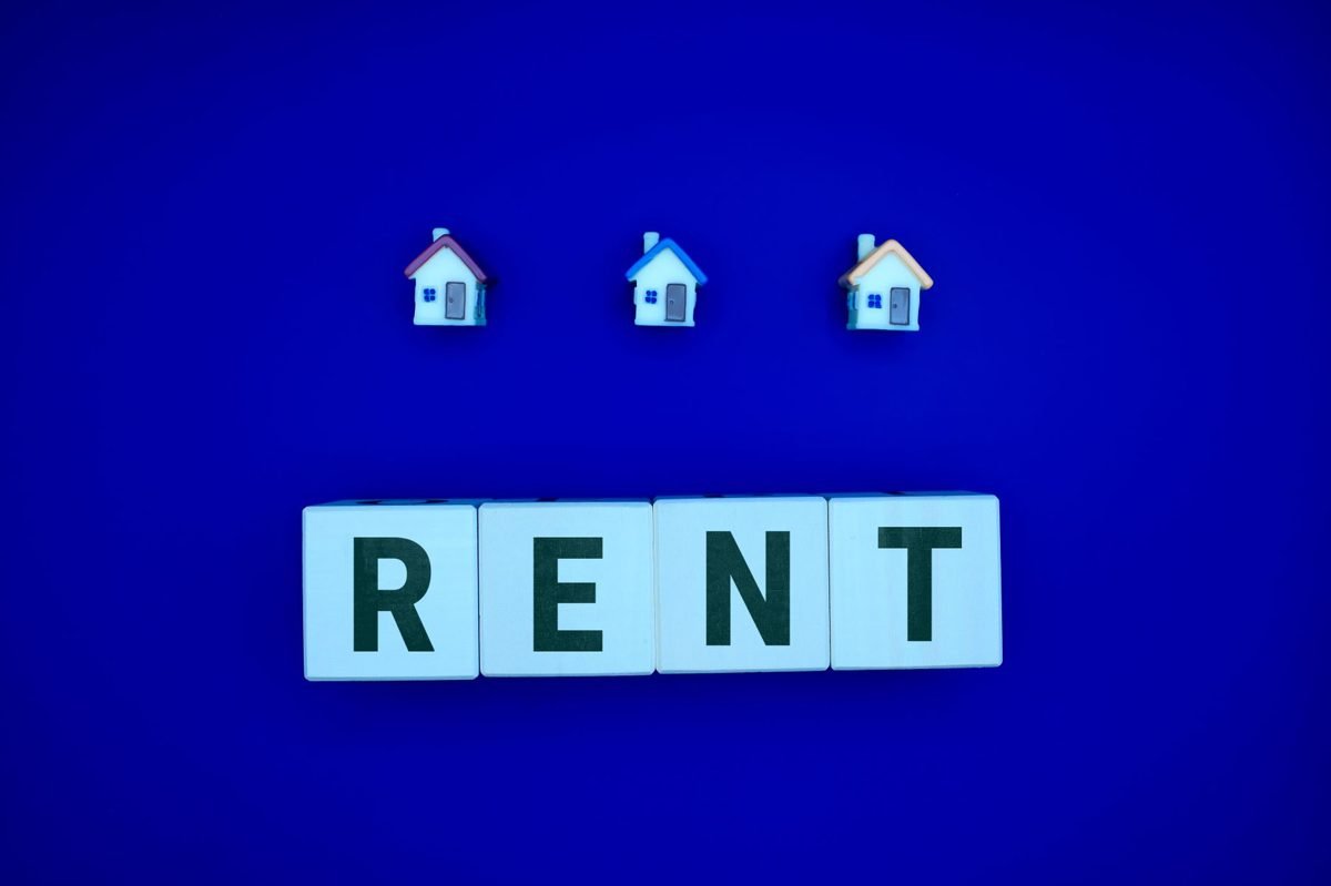 Small model house next to house keys and a calculator representing the rent versus buy decision